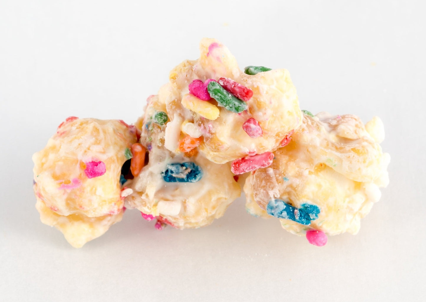 Four chocolate-coated popped popcorn kernels with sprinkles.