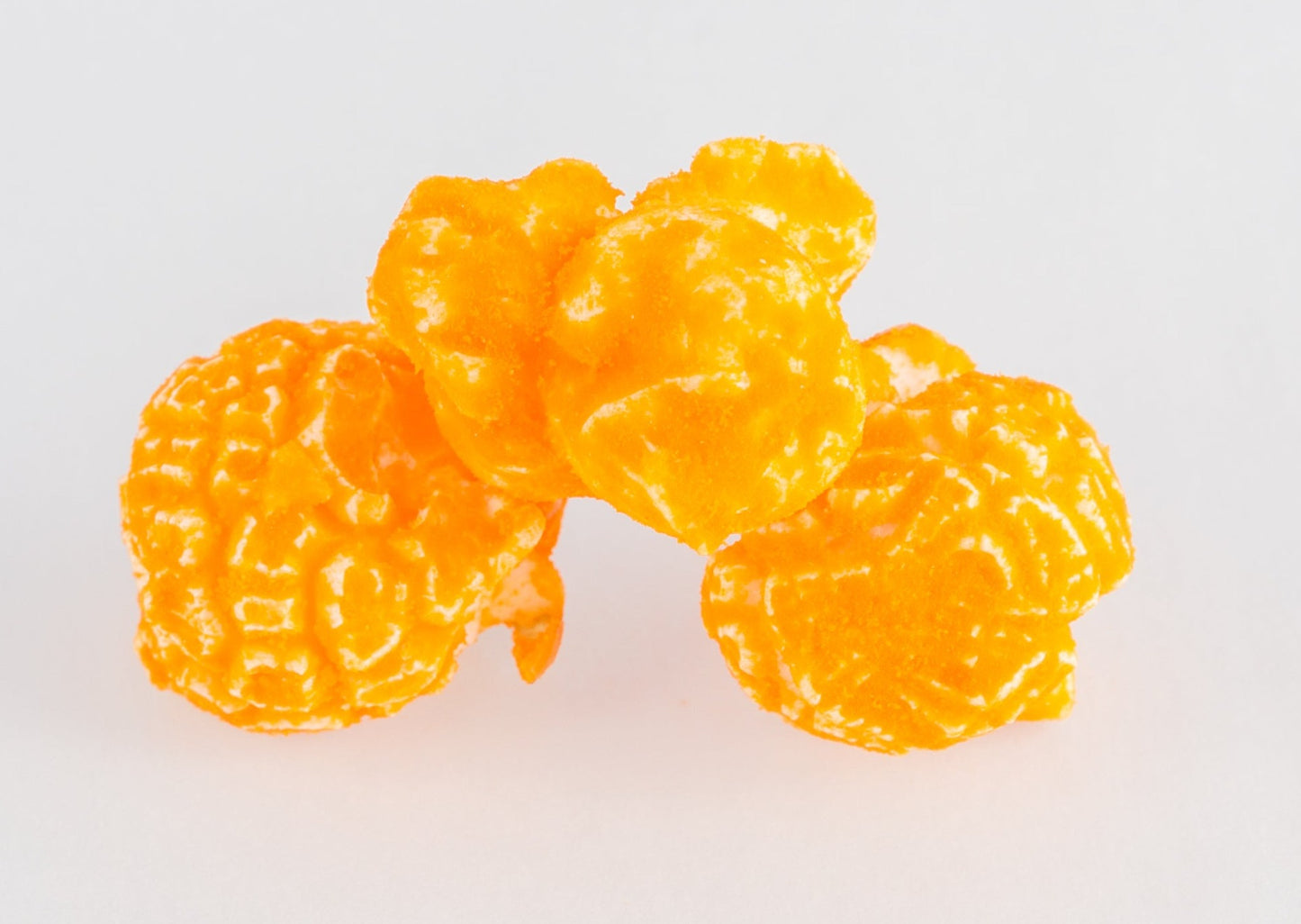 A stack of three cheese-coated popped popcorn kernels.
