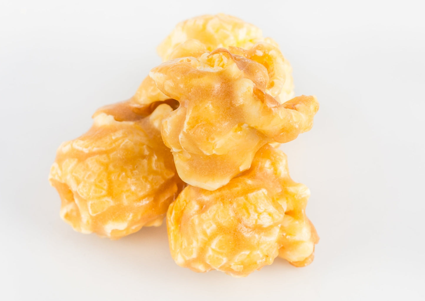 Three pieces of popped popcorn kernels covered in caramel and salt.