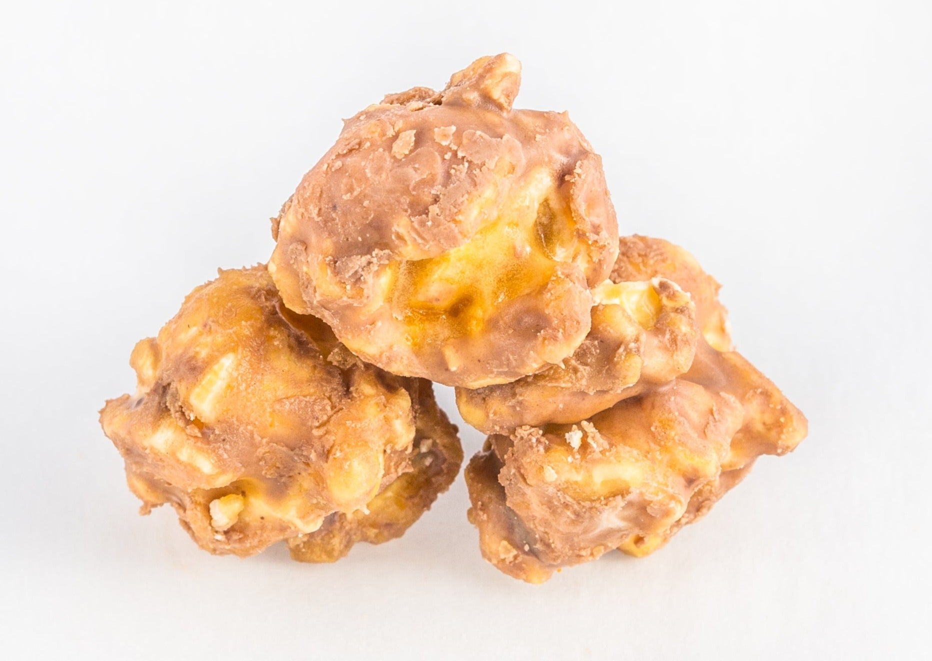 Three pieces of popped popcorn covered with caramel, butterscotch and peanut butter.