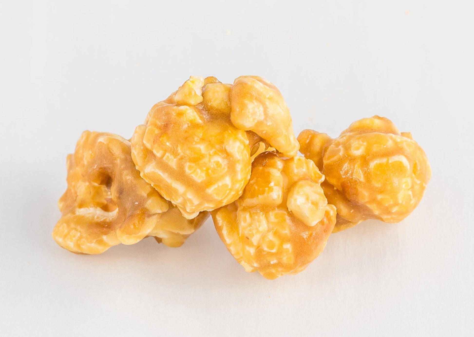 A stack of four caramel-coated popped popcorn kernels.