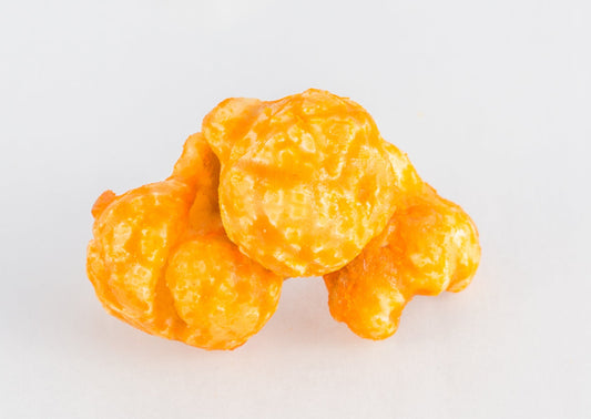 A stack of three cheese and caramel-coated popped popcorn kernels.
