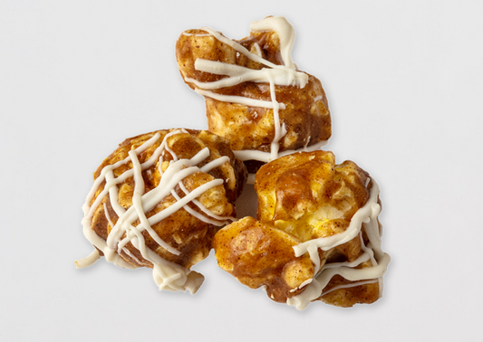 Three kernels of cinnamon-coated popped popcorn drizzled with white frosting.