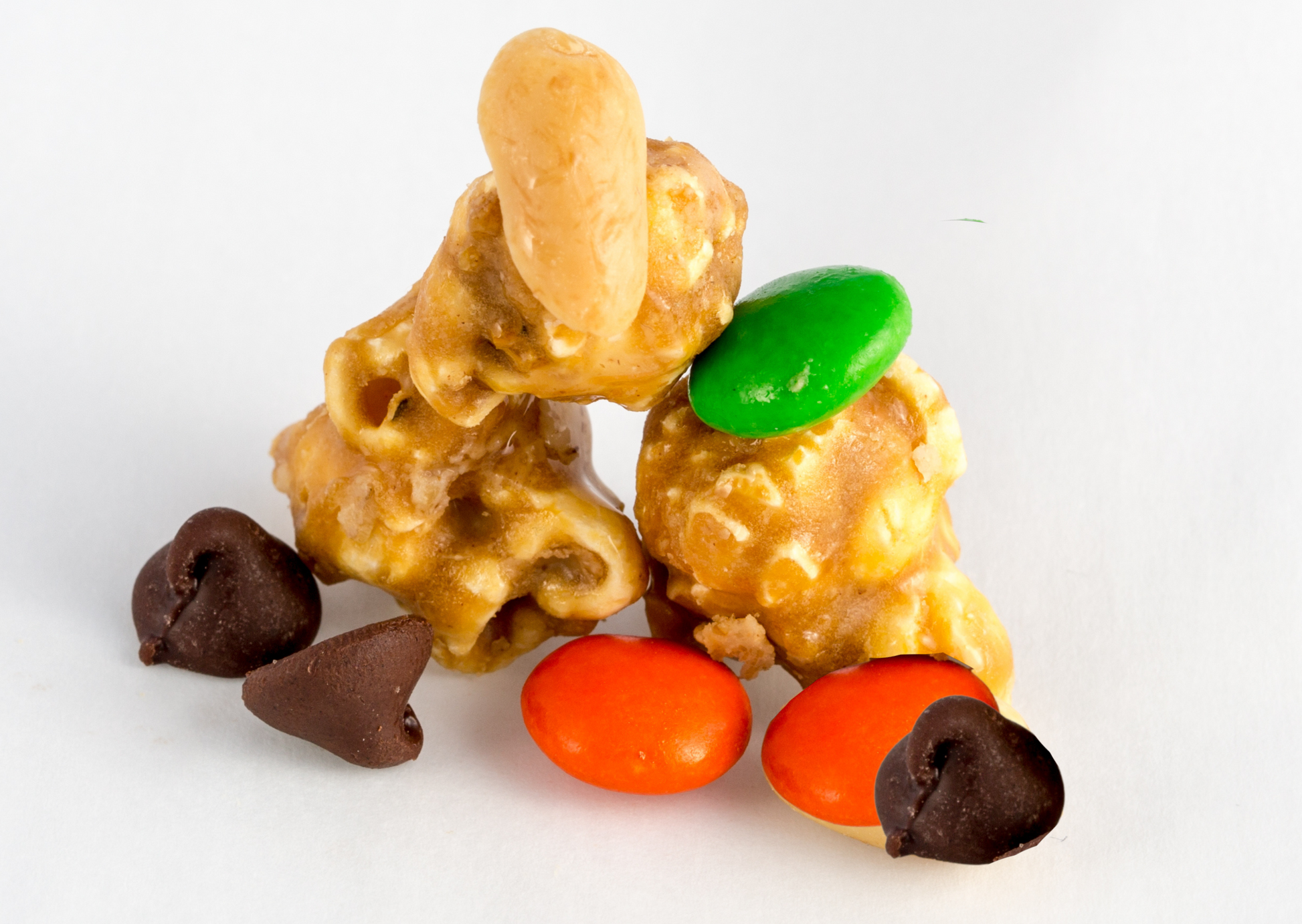 Three pieces of peanut butter-covered popcorn with M&Ms and chocolate chips.