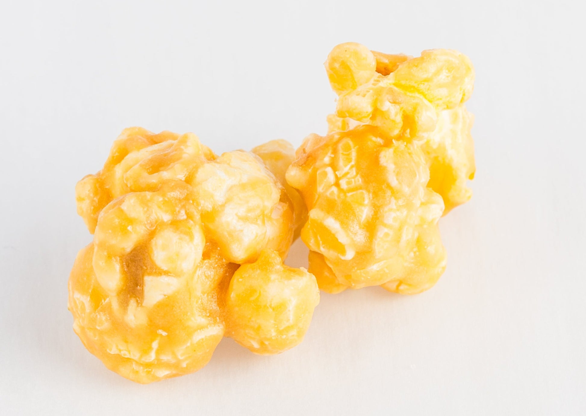 Two kernels of popped popcorn covered in caramel.