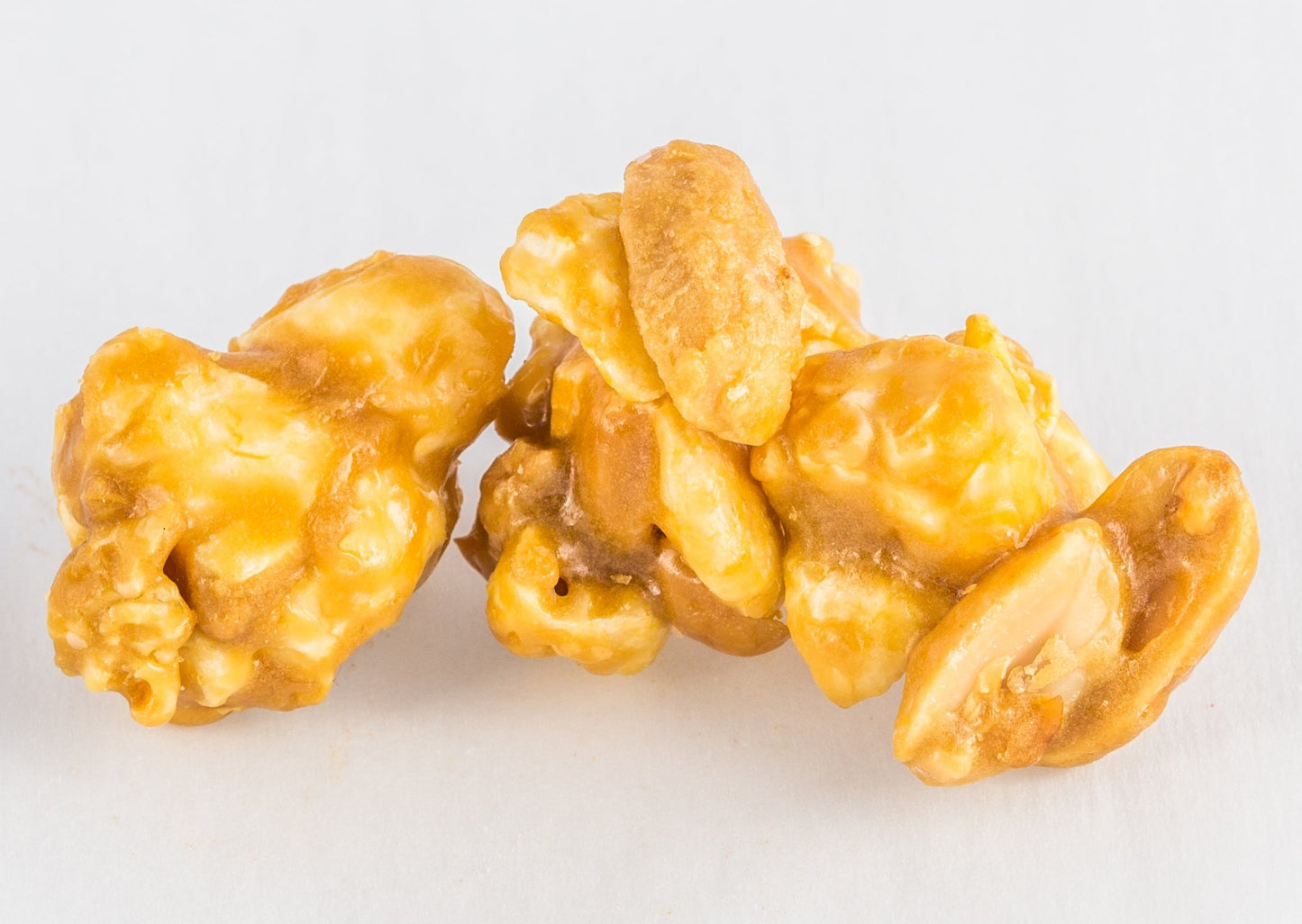 Four kernels of popped popcorn with caramel and peanuts.