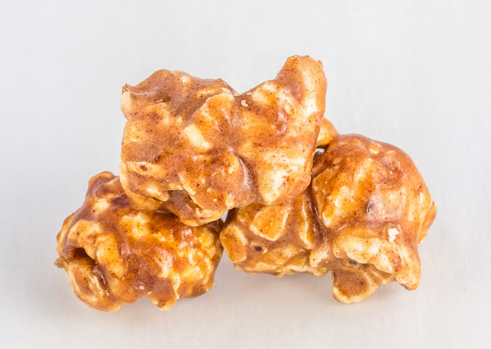 Three pieces of popcorn covered in caramelized with cinnamon.